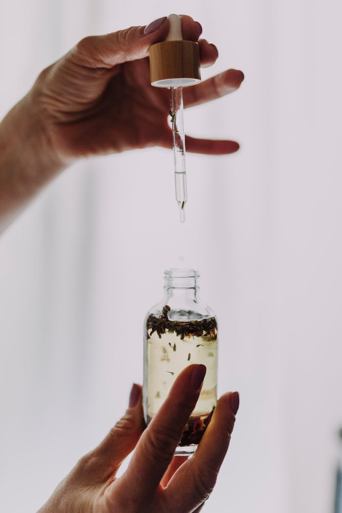 service-04 Close-up of hands using a dropper with an essential oil bottle, perfect for wellness themes.