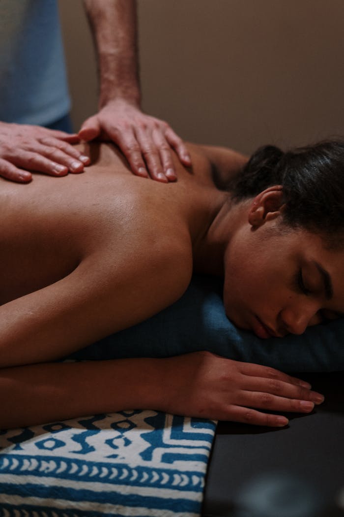 service-06 Relaxing massage therapy session with therapists hands on womans back in spa setting.